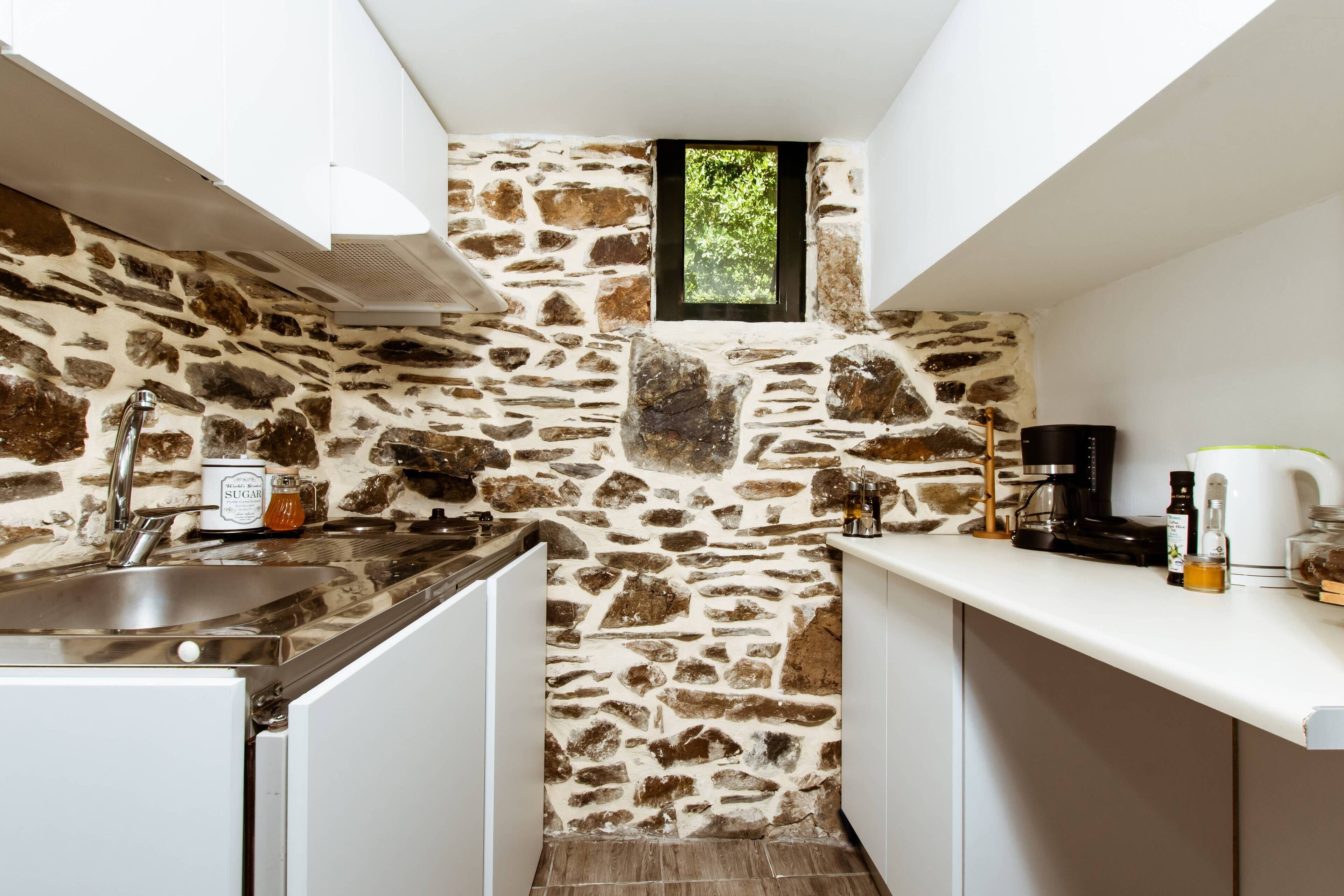 A kitchen with a stone wall, a window, and a coffee machine.