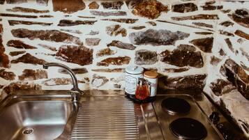 A kitchen with a stone wall backsplash, stainless steel sink, and stove.