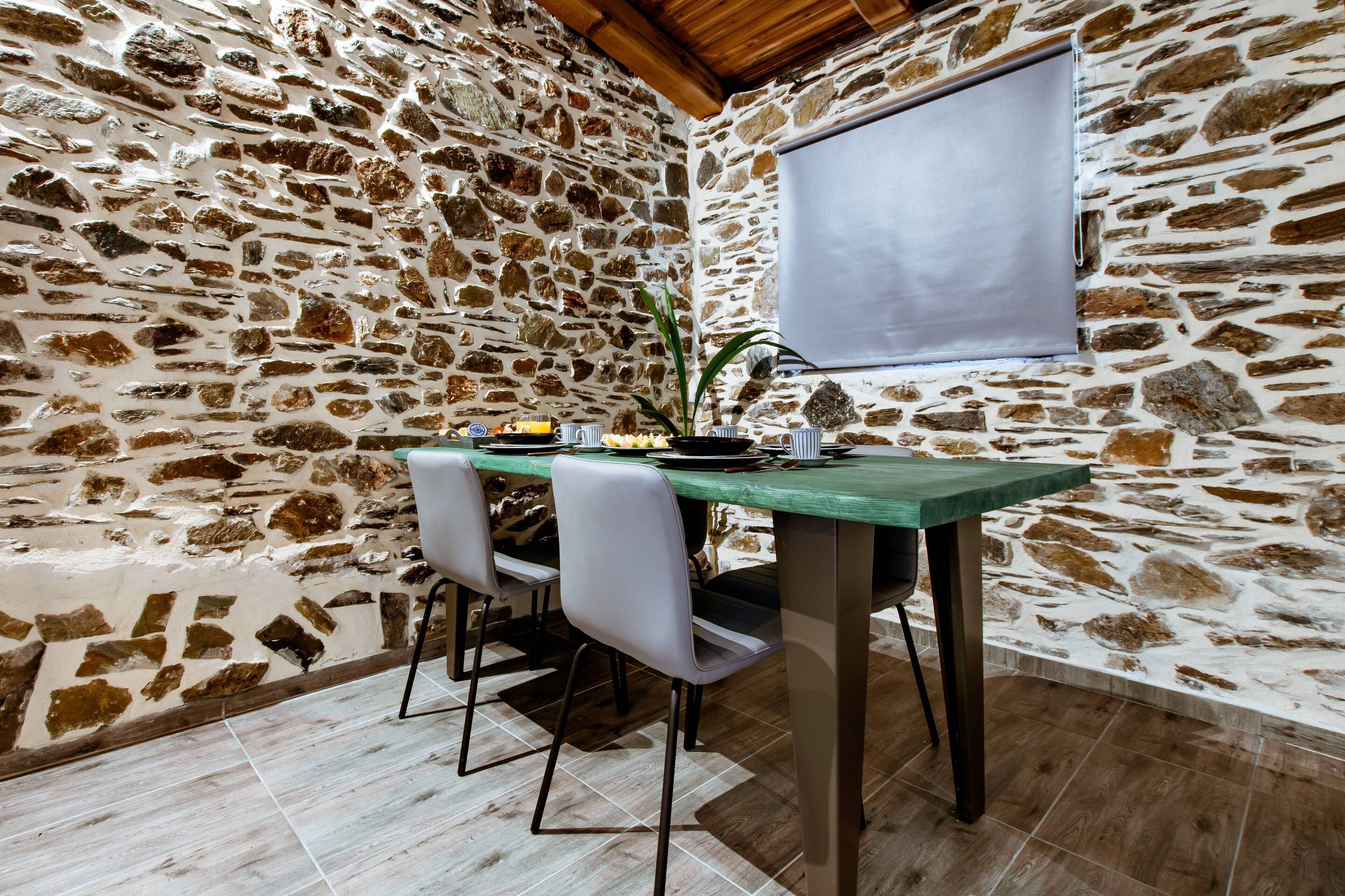 A stone-walled room with a dining table and chairs.