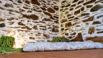 Interior de una pared de piedra con un cojín estampado en el suelo.