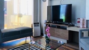 A modern living room with a flat-screen TV, a sofa, a coffee table, and a potted orchid. - IDEAL for WORK and confort JACUZZI and GRILL (Arequipa)