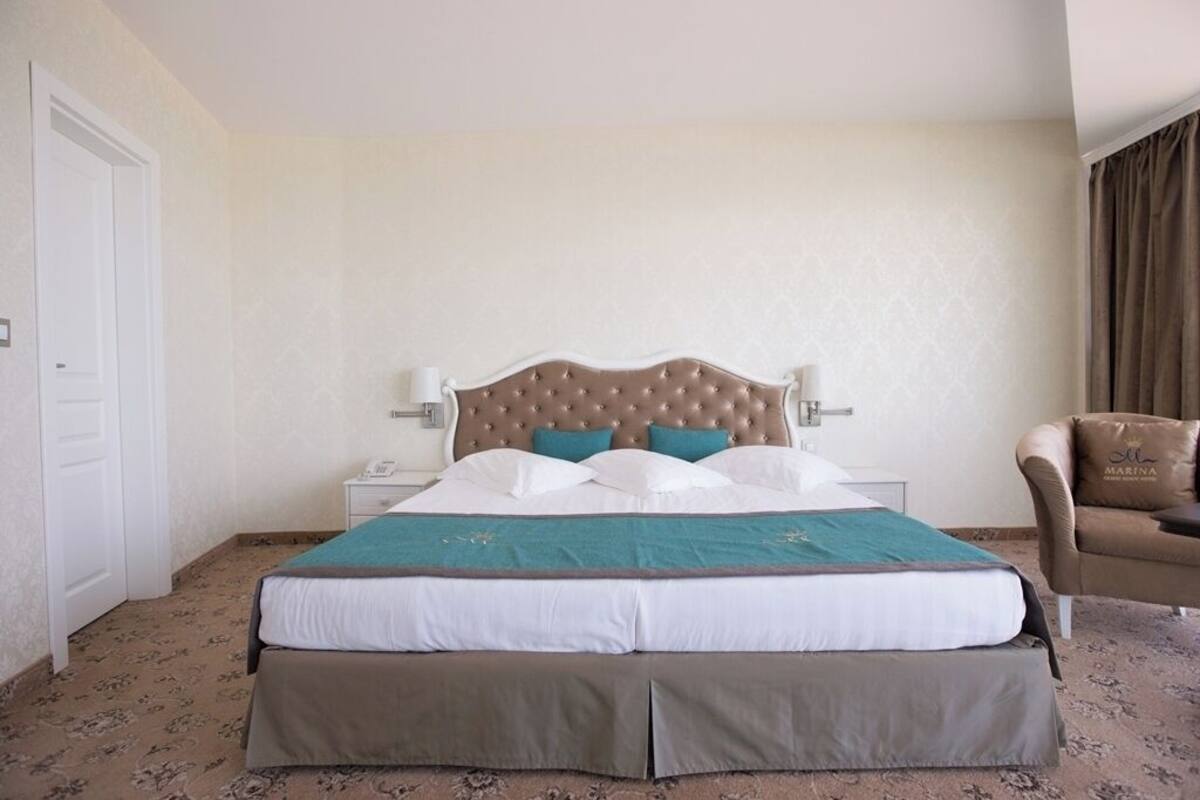 A hotel room with a large bed, a nightstand, a chair, and a door.