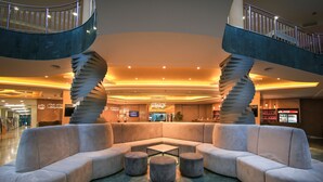 A modern lobby with a central seating area, a spiral staircase, and a Coca-Cola refrigerator.