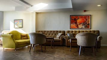 Un salon moderne avec un canapé jaune, deux fauteuils et un canapé marron. Un grand tableau orne le mur, et une photo encadrée est accrochée au-dessus du canapé.