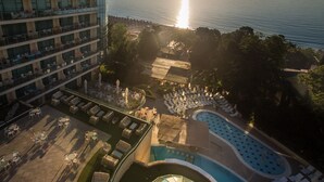 A hotel with a pool, outdoor seating, and a view of the sea.
