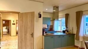 Una cocina moderna con piso de madera clara, un ventanal con cortinas y vistas al exterior.