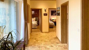 Un pasillo con suelo de baldosas que conduce a un dormitorio con cama y mesita de noche.