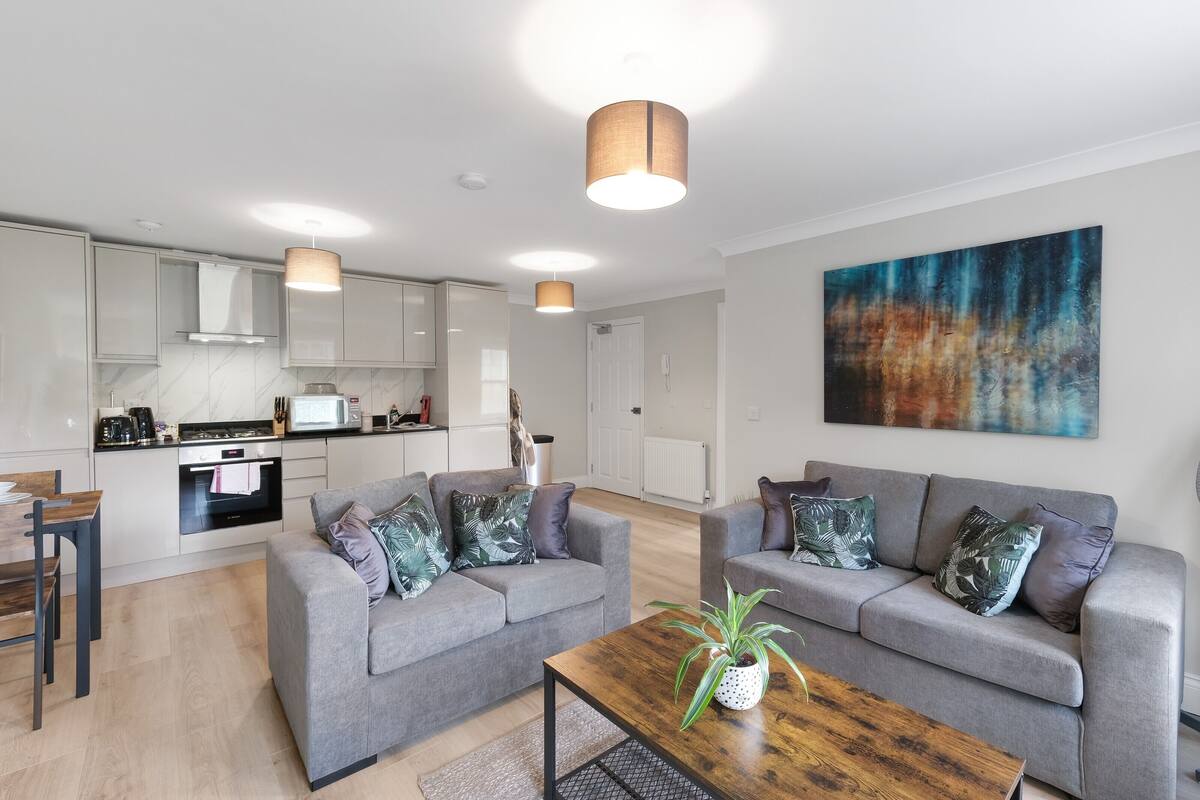 A modern living room with two grey sofas, a wooden coffee table, and a large abstract painting on the wall.