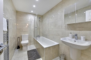 Une salle de bain moderne équipée de toilettes, d’une baignoire et d’un lavabo.