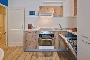 A compact kitchen with wooden cabinets, a microwave, a built-in oven, and a dishwasher.