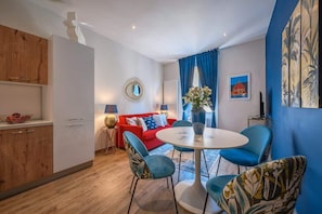 A modern living room with a red sofa, blue chairs, a round table, and a blue wall.