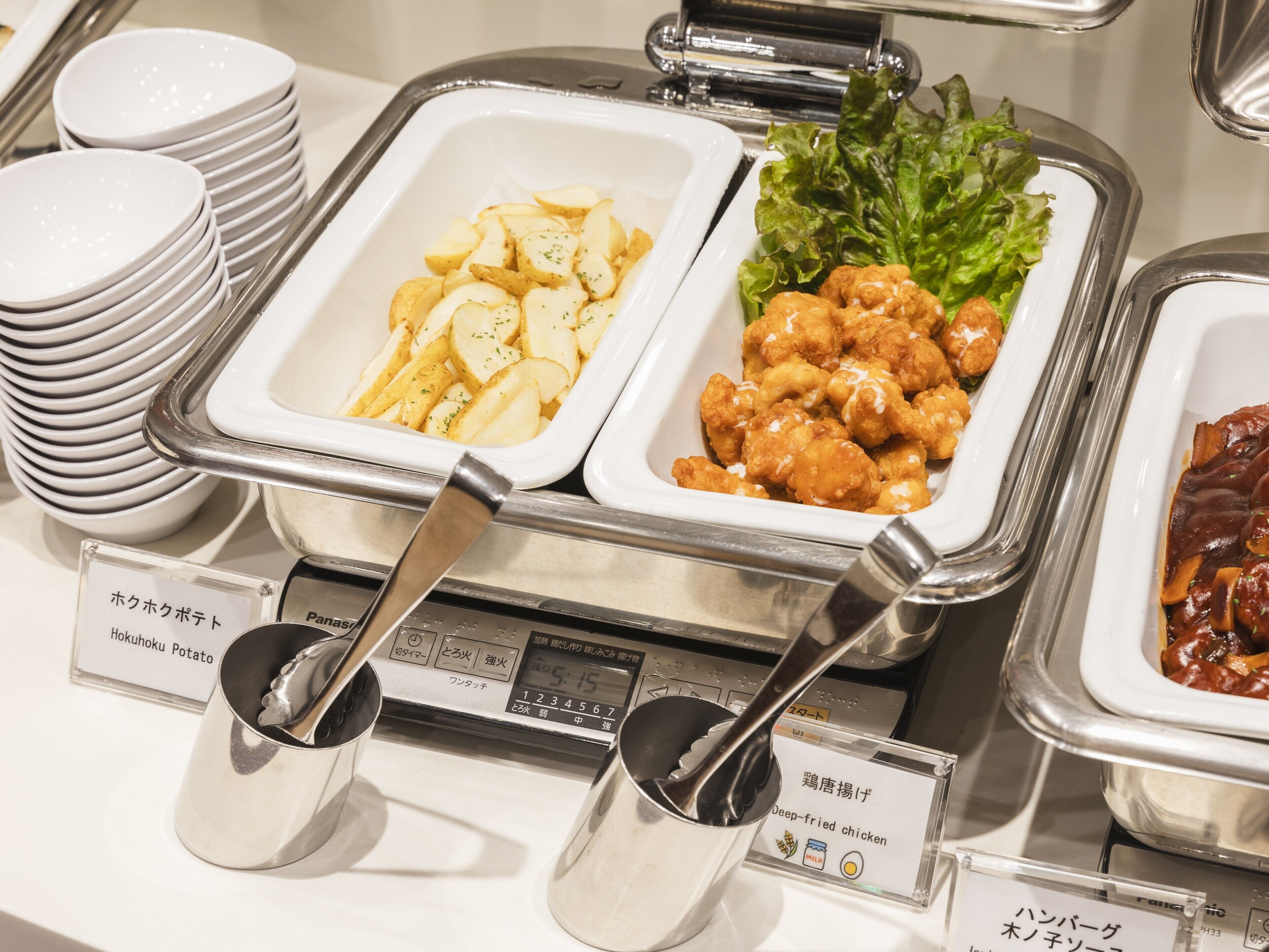 A buffet with labeled dishes including potatoes, chicken, and a meat dish.