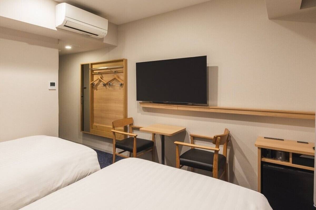 A hotel room with two beds, a TV, a desk, and a wardrobe.