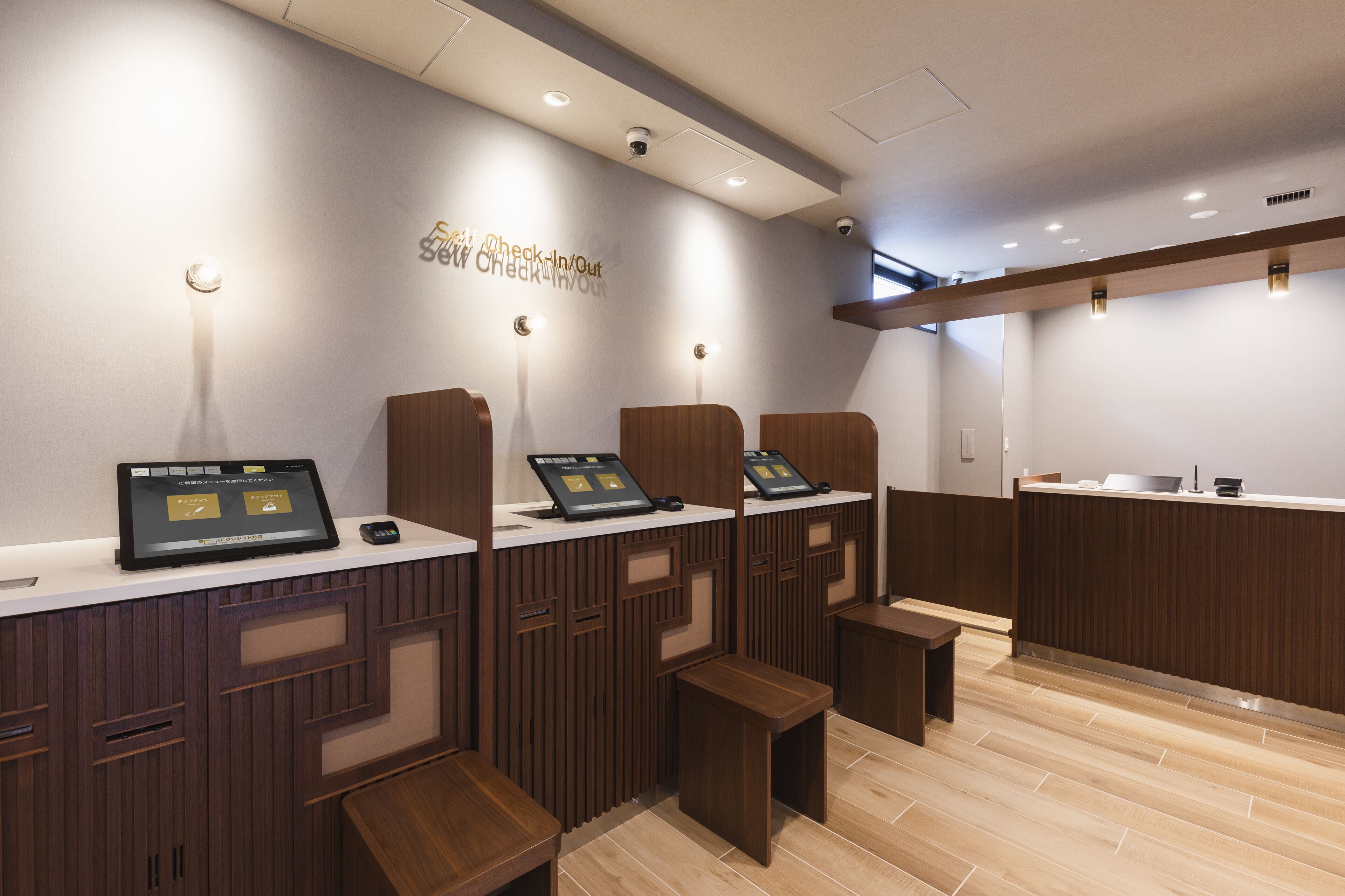 A modern reception area with a check-in/out desk, seating, and a wooden floor.