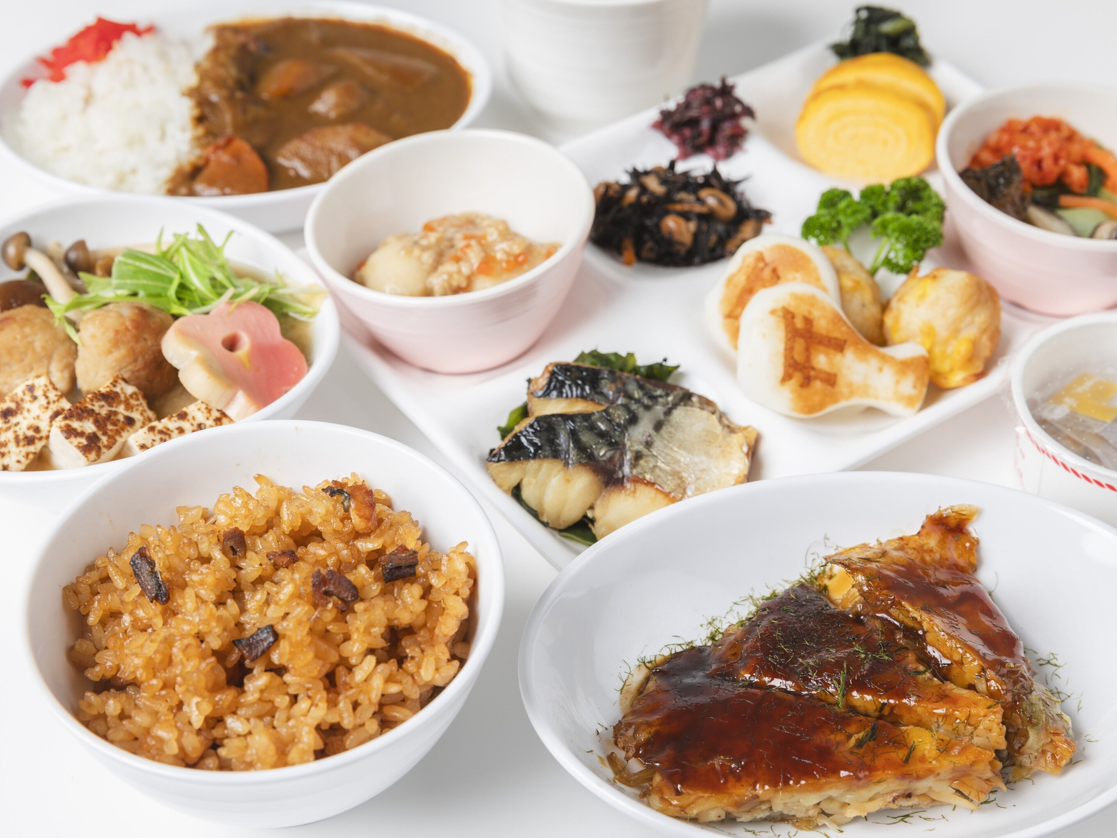 Una variedad de platos que incluyen arroz, pescado y verduras, lo que sugiere una amplia selección de comidas.