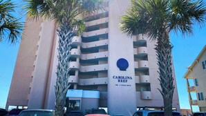 En byggnad med flera våningar, med en skylt som visar texten ”CAROLINA REEF” och ”1501 S. OCEAN BLVD.”.