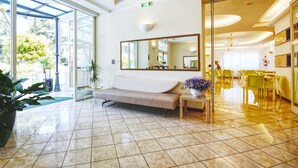 Un vestíbulo de hotel con un banco, un espejo grande y un comedor con sillas amarillas.