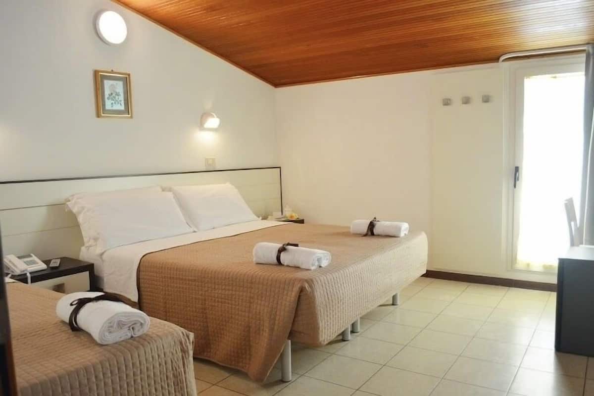Une chambre d’hôtel avec un grand lit, deux tables de chevet, une petite table de nuit et un petit bureau avec une chaise.