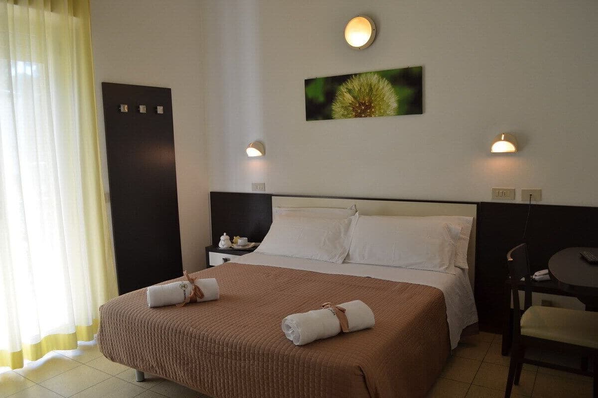 Une chambre d’hôtel comprenant un lit, des tables de chevet, une chaise et un tableau accroché au mur.
