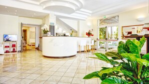 Un vestíbulo de hotel con una recepción, una escalera y un comedor.
