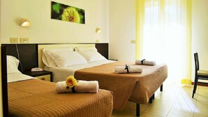 Habitación de hotel con dos camas, un ventanal con cortinas amarillas, un cuadro colgado en la pared y una silla.
