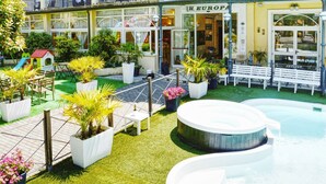 Un patio con jacuzzi, plantas en macetas, una zona de juegos infantiles y un edificio con un cartel que dice EUROPA.