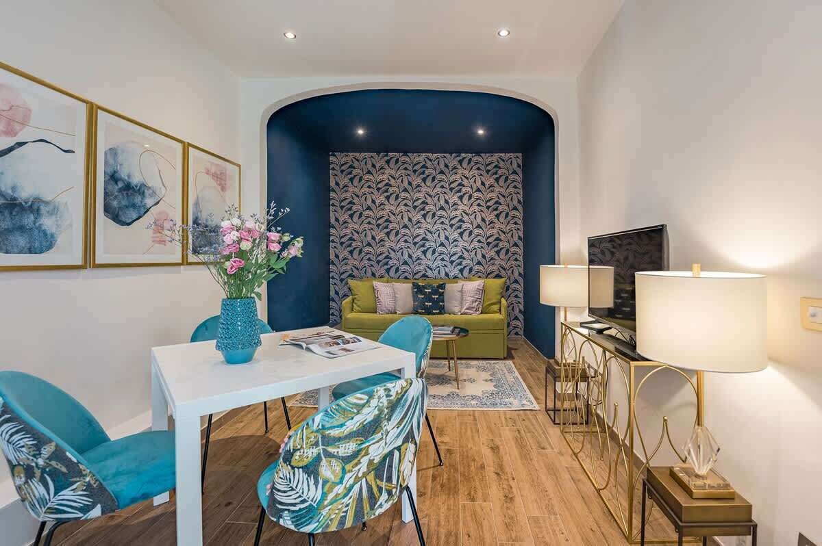 A modern living room with a sofa, chairs, a dining table, and a TV.