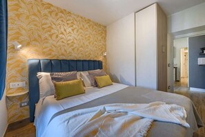 Une chambre à coucher avec un lit, une tête de lit et un mur orné d’un motif floral.
