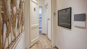 A hallway with a door leading to a bathroom, a framed sign on the wall, and a decorative wall piece. - Macci A) Modern Elegant Apartment S. Ambrogio (Firenze)