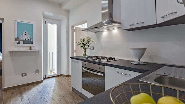 A modern kitchen with white cabinets, a gas stove, and a stainless steel sink. - Macci A) Modern Elegant Apartment S. Ambrogio (Firenze)