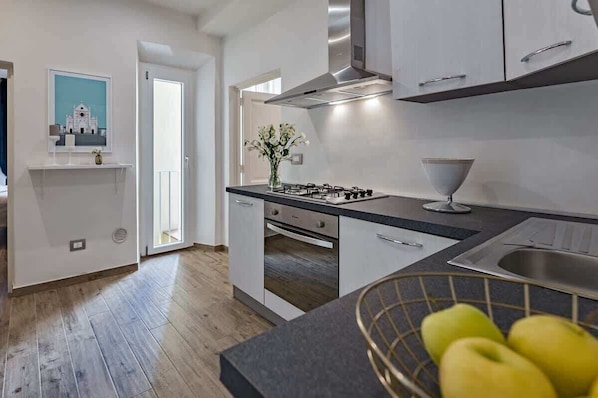 A modern kitchen with white cabinets, a gas stove, and a stainless steel sink.