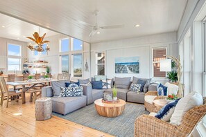 A spacious living room with a large dining table, comfortable seating, and a view of the outdoors.