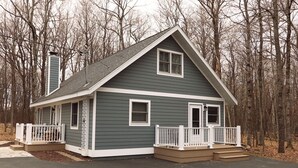 A two-story house with a gabled roof, white trim, and a front porch with a white railing.