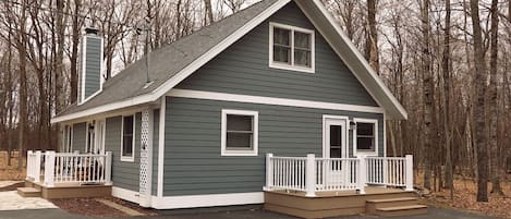 Een twee verdiepingen tellend huis met een puntige kap, witte sierlijsten en een veranda met een witte balustrade.