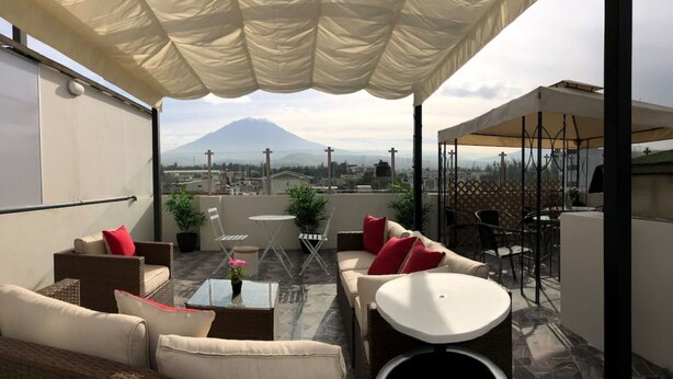 Une terrasse sur le toit avec des sièges extérieurs, une vue sur une montagne et un espace couvert avec des tables et des chaises.
