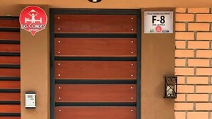 Une entrée d’immeuble avec une grande porte en bois, une enseigne rouge au-dessus de la porte et une petite enseigne sur le côté droit.