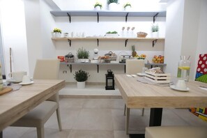 Une cuisine moderne avec des plans de travail en bois, des armoires blanches et une variété de plantes et d’ustensiles de cuisine.