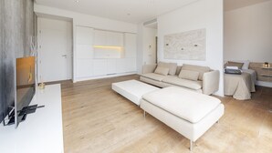 A modern living room with a sofa, ottoman, and a flat-screen TV mounted on the wall. - Penthouse Dalias with private jacuzzi in Port de Pollensa (Puerto Pollensa)