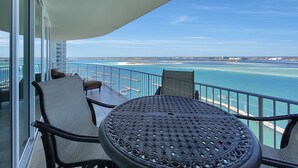 A balcony with a table and chairs, overlooking a coastal view with a clear sky. - DOWN BY THE BAY! ASK ABOUT DISCOUNTS! 3 Bedroom Unit Amazing bay views! (Orange Beach)