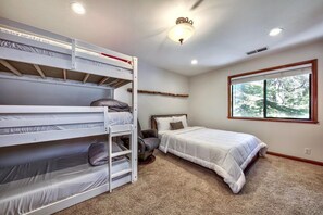 A bedroom with bunk beds, a single bed, a window with a view, and a ceiling light fixture.