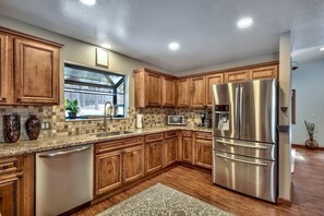 A kitchen with wooden cabinets, stainless steel appliances, a window, and a dishwasher.