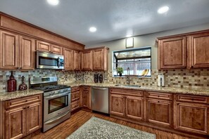 Una cocina con armarios de madera, electrodomésticos de acero inoxidable, una ventana con vistas y un salpicadero de azulejos.