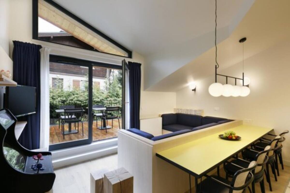 A modern kitchen with a dining area, large windows, and a view of the outdoors.