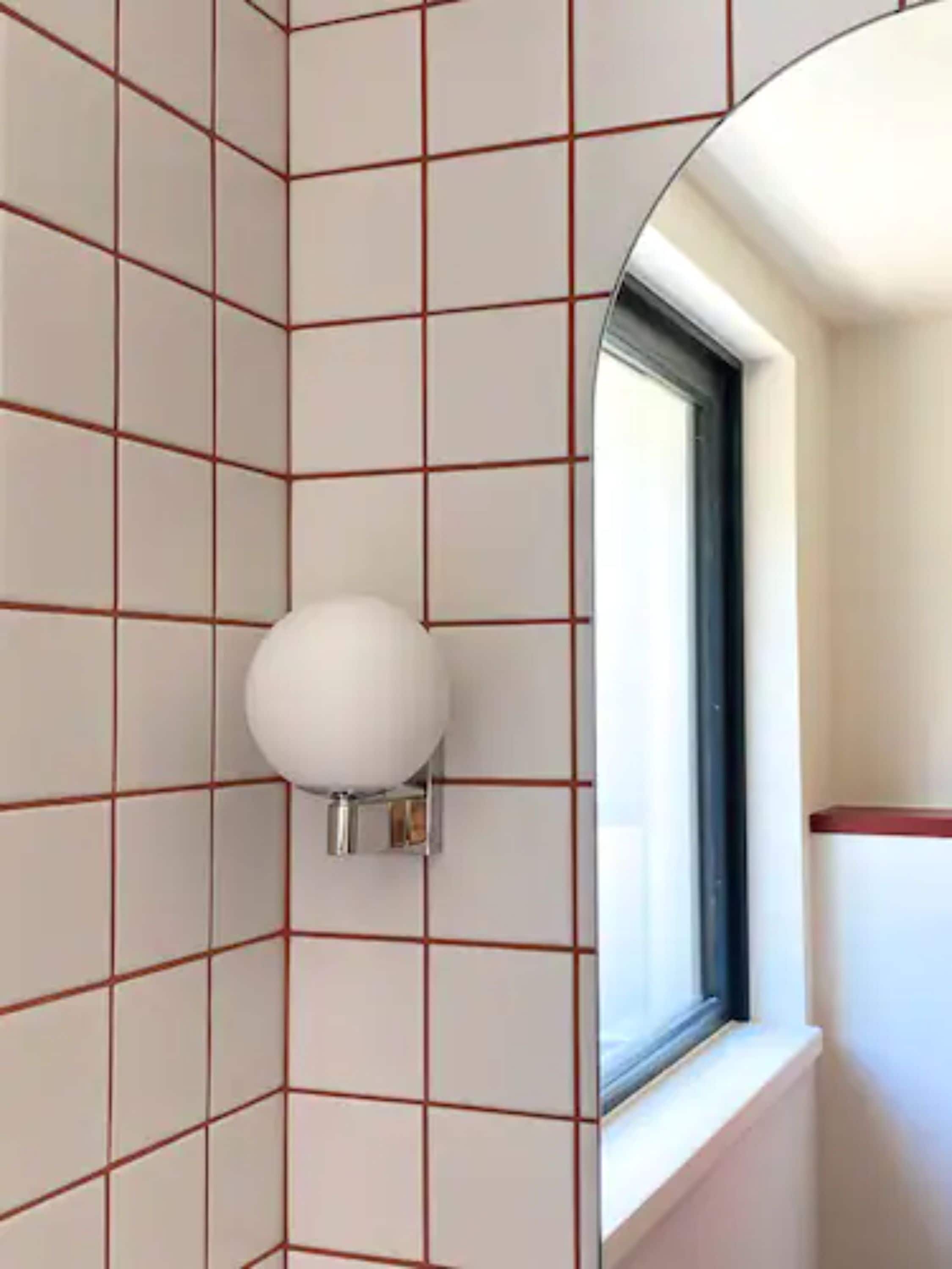 Un baño con azulejos blancos y una ventana.