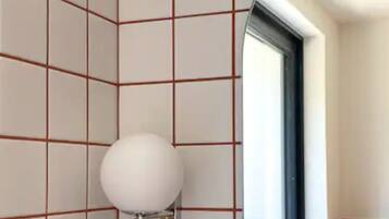 Un baño con azulejos blancos y una ventana.