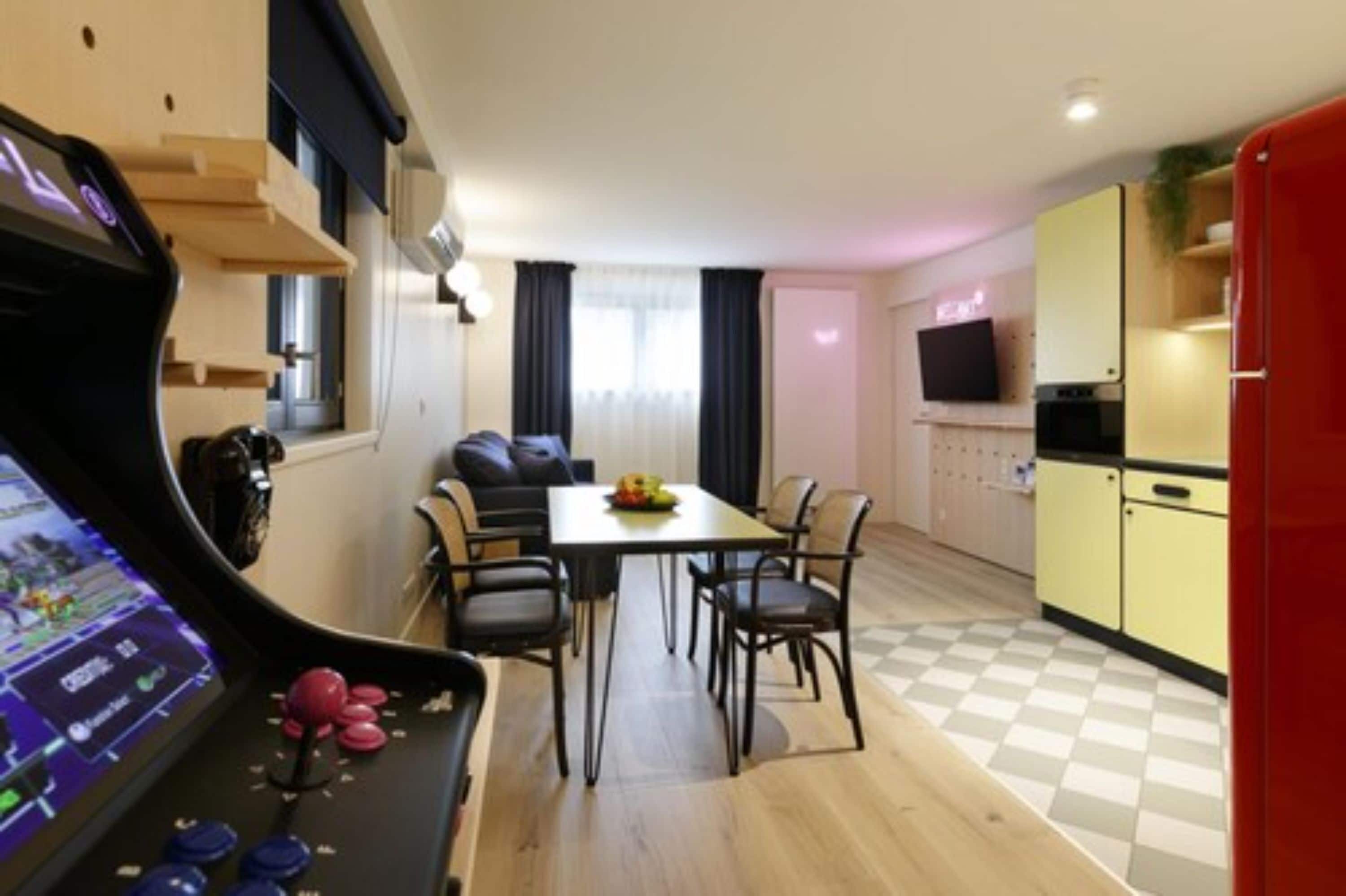A compact living space with a dining area, kitchenette, and a gaming console.