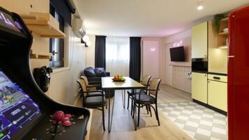 A compact living space with a dining area, kitchenette, and a gaming console.