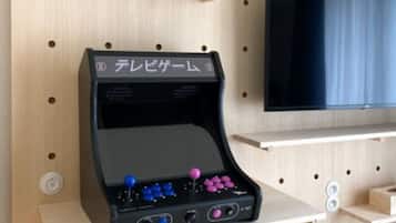 A gaming console on a wooden shelf with a TV mounted on the wall above.