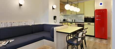 A compact kitchen with a dining area, a red refrigerator, and a blue sofa.