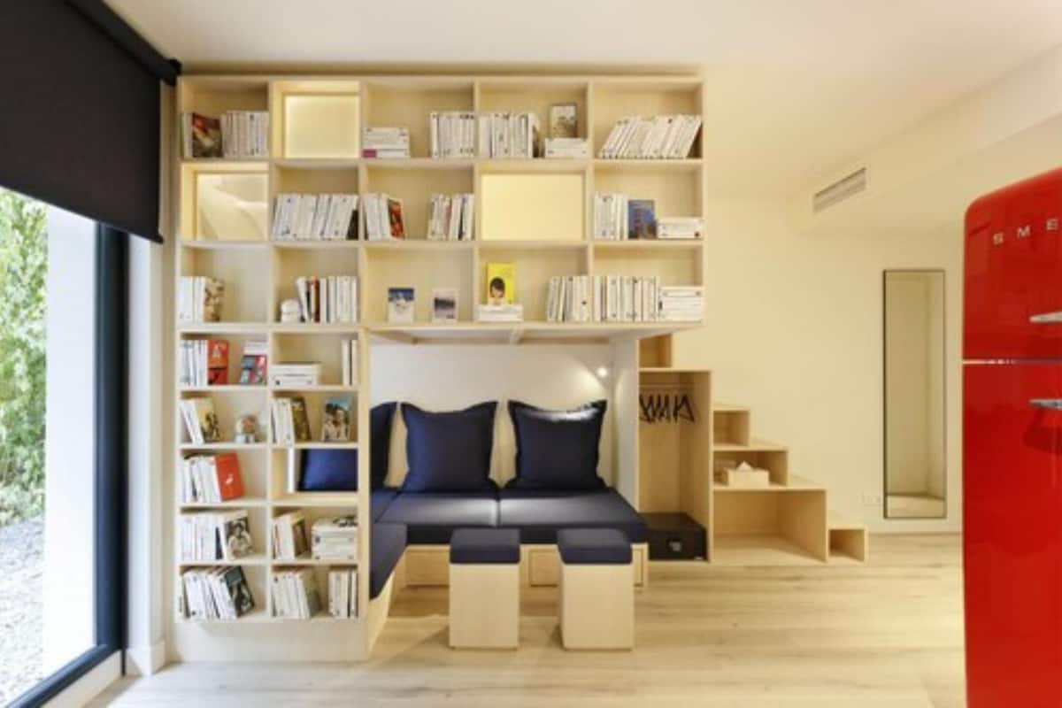 A modern room with a built-in bookshelf, a sofa, and a red appliance.